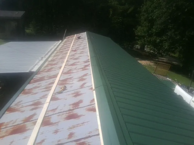 Old rusted panels beside newly installed green metal roofing — Wind Damage Roof Repair by Roofing Brothers in Mequon