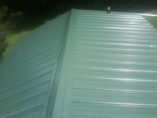 New green metal panels meeting at the ridge of a roof — Flat Roof Repair work by our crew in Mequon