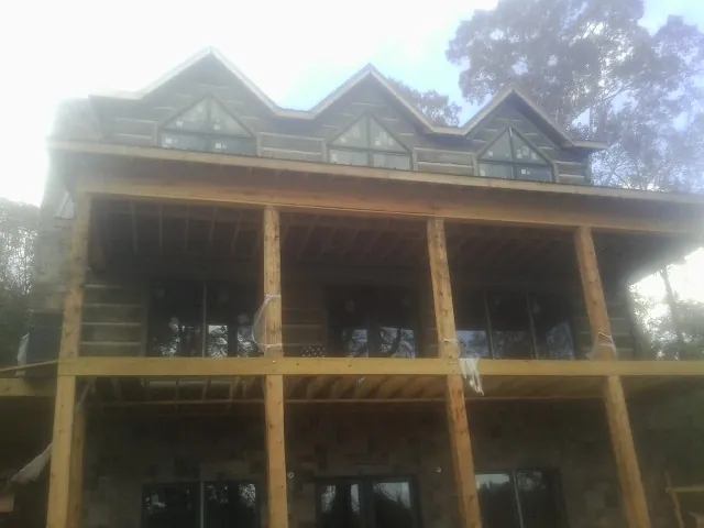 Dormers and porch framing on a large log home under construction — Roof Coating work by our crew in Mequon