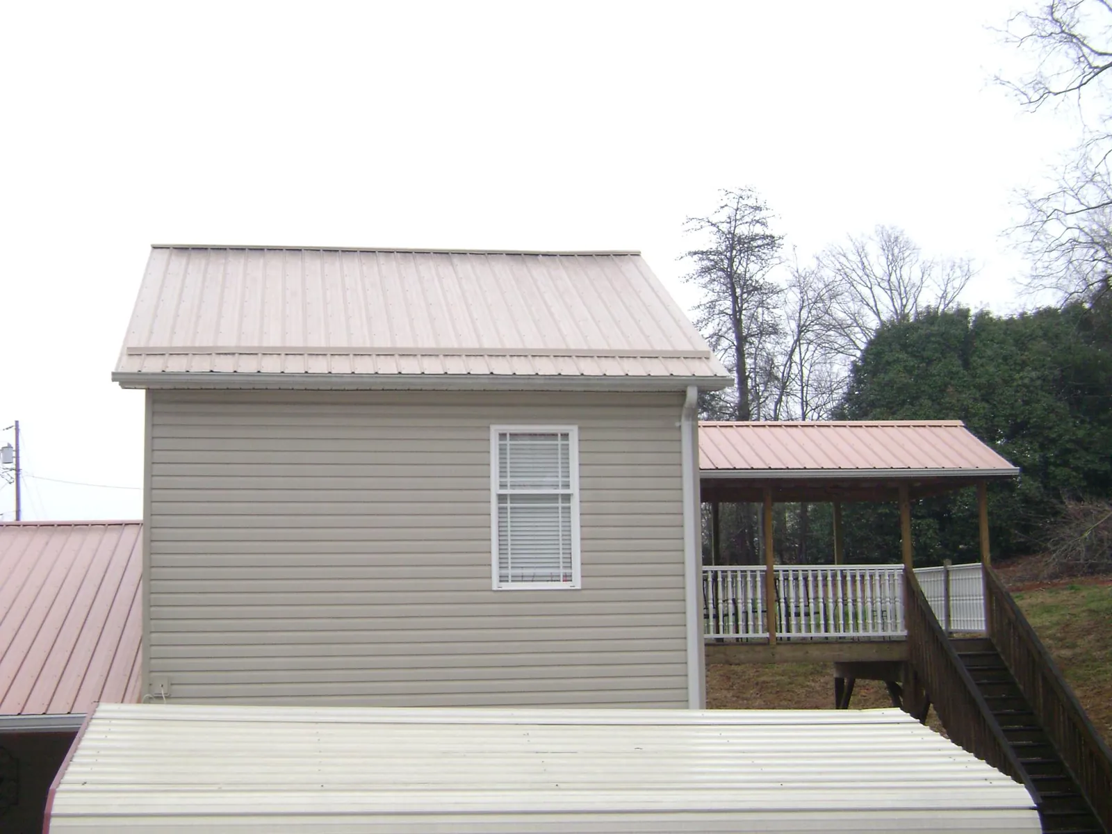 Tan metal roofs on a two story addition and attached porch, from a Roof Replacement job in Mequon