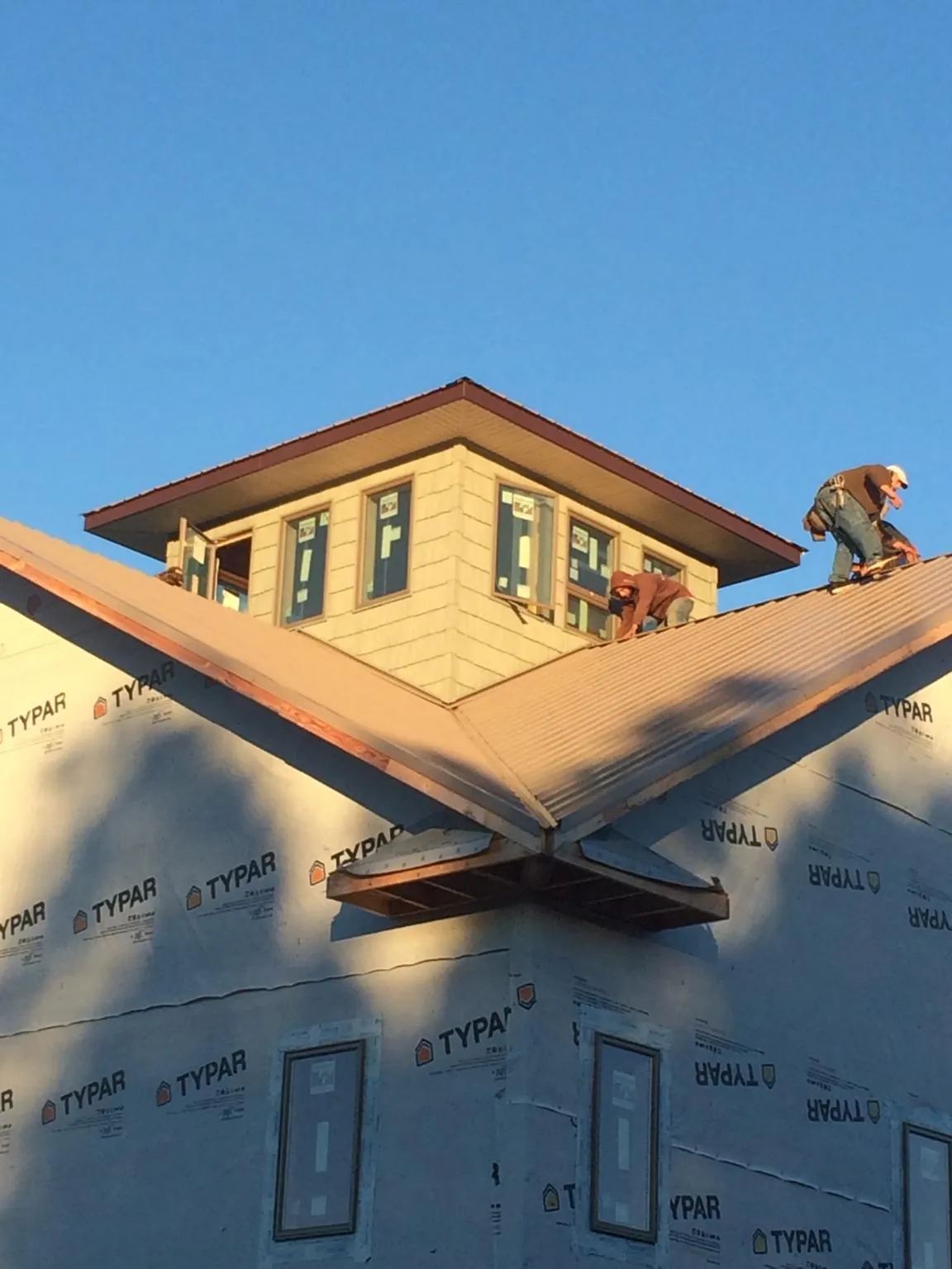 Roofers working around a rooftop cupola on a new metal roof at sunset — Roof Waterproofing in Mequon by Roofing Brothers